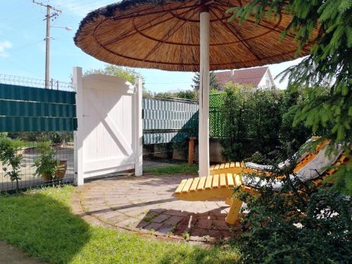 a patio with a bench and an umbrella and a fence at Apartman TESLA 29 in Veternik