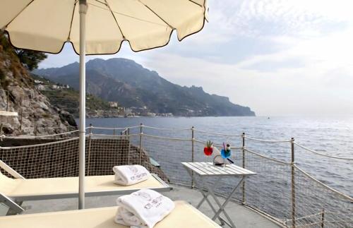 a boat with a table and an umbrella and the water at Ravello Art Hotel Marmorata in Ravello