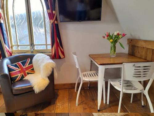 une salle à manger avec une table et une chaise avec un vase de fleurs dans l'établissement Quaint Studio Loft Room nr Hampton Court, à Thames Ditton