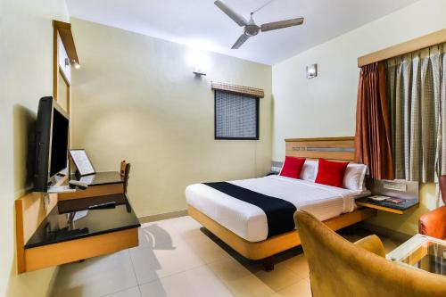 a hotel room with a bed and a television at Capital O Grand Plaza in Coimbatore