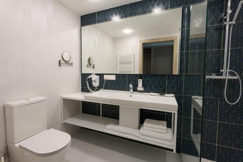 a bathroom with a sink and a toilet and a mirror at Suncity Hotel & SPA in Šiauliai