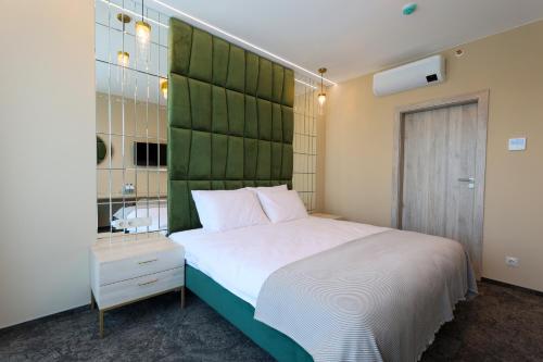 a bedroom with a large bed with a green headboard at Suncity Hotel & SPA in Šiauliai