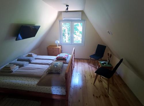 um quarto no sótão com uma cama e uma janela em Mókuska erdőszéli faházikó em Parád