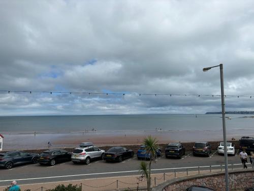 ein Parkplatz mit Autos neben dem Strand in der Unterkunft The Great Western B&B in Paignton