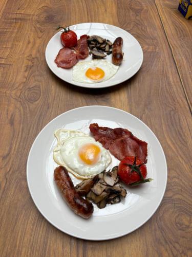 zwei Teller mit Frühstücksspeisen auf einem Holztisch in der Unterkunft The Great Western B&B in Paignton