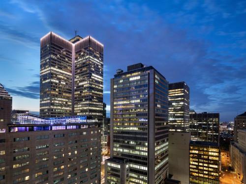 un groupe de grands bâtiments dans une ville la nuit dans l'établissement Fairmont The Queen Elizabeth, à Montréal