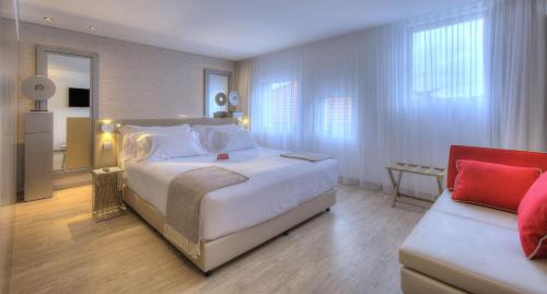 a bedroom with a large white bed and a couch at NH Collection Porto Batalha in Porto