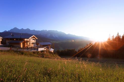 a house on the side of a hill with the sunset at Alpenchalets Reiteralm by ALPS RESORTS in Schladming