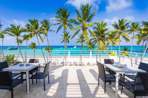 a restaurant on the beach with palm trees and the ocean at Dream Punta Cana Beachfront Apartment - 4-Bedroom Penthouse with Rooftop BBQ & Ocean Views in Punta Cana