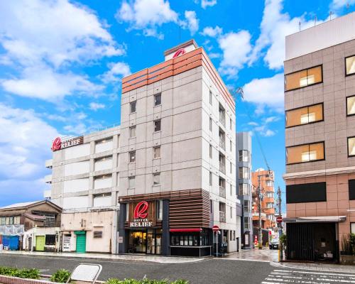 a tall white building on a city street at HOTEL RELIEF Kokura Station in Kitakyushu