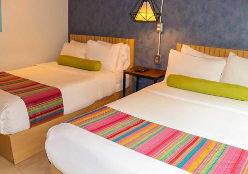 a hotel room with two beds with colorful sheets at Estancias VIVE MX wtc in Mexico City