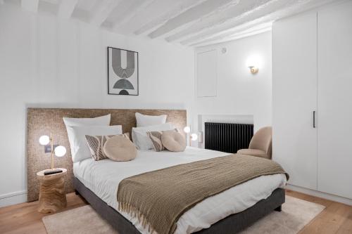 um quarto branco com uma cama grande e almofadas em Appartement Cosy à 9 min à Pied de la Cathédrale NOTRE DAME em Paris