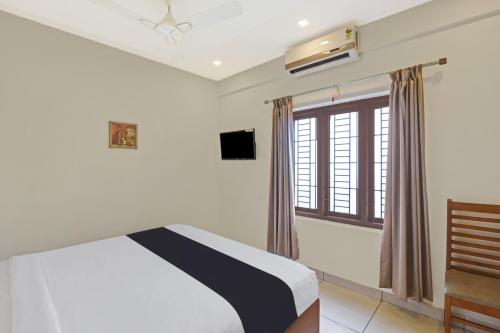 um quarto com uma cama e uma janela em Hotel O AURA RESIDENCY em Kannur