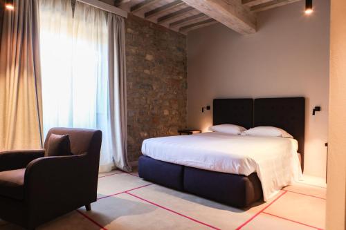 - une chambre avec un grand lit et une chaise dans l'établissement Castello Di Meleto, à Gaiole in Chianti