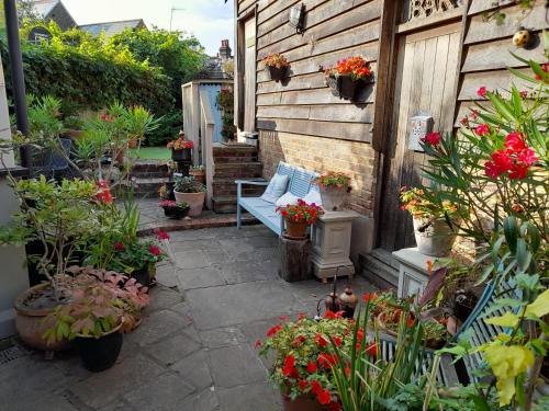 un jardin avec des plantes en pot et un banc bleu dans l'établissement Quaint Studio Loft Room nr Hampton Court, à Thames Ditton