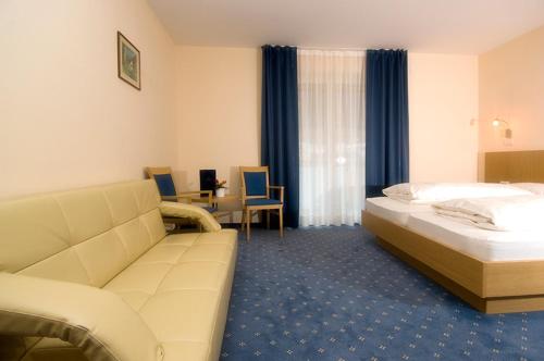 a hotel room with a bed and a couch at Hotel Weingarten in Caldaro