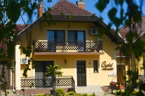 a yellow house with a balcony at Crystal Apartman in Mórahalom