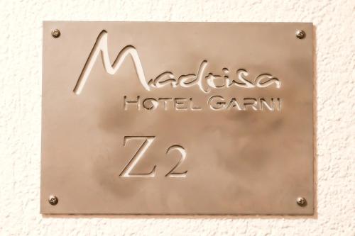 una señal para un hotelgm colgado en una pared en Hotel Garni Madrisa, en Brand