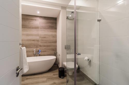 a bathroom with a tub and a toilet and a shower at STAY Menlyn in Pretoria