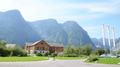 un grand bâtiment avec des montagnes en arrière-plan dans l'établissement Holiday Homes Obertraun/Oberösterreich 86, à Obertraun