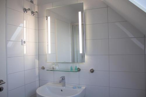 La salle de bains blanche est pourvue d'un lavabo et d'un miroir. dans l'établissement Cuxlandhotel Studio 204, à Dorum Neufeld