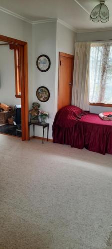 a bedroom with a red bed and a window at The_Cozy_Batch With a rural view in Whanganui