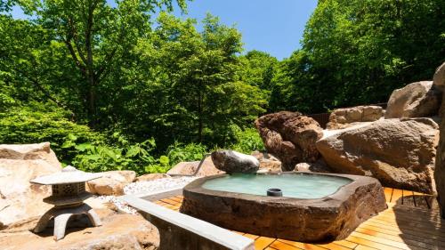 een stenen fontein op een houten terras met rotsen bij Mogamitakayu Zenshichinoyu Ohira in Zao Onsen