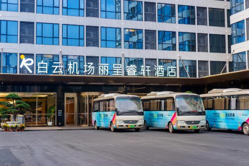 tre autobus parcheggiati di fronte a un edificio di Guangzhou Baiyun Airport COCO Hotel a Huadu