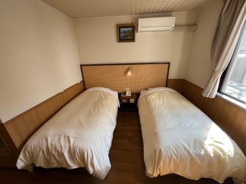 twee bedden naast elkaar in een kamer bij Hotel Marsh Land in Kushiro