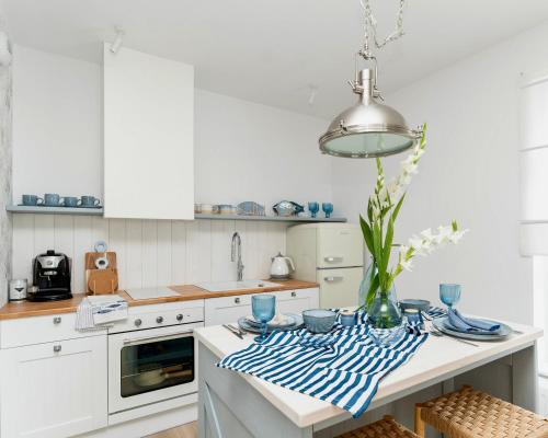 a white kitchen with a table with a vase of flowers at Apartament Aqua Przystań 80 - Rumia Novum in Rumia