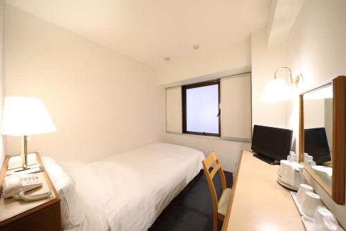 Cette chambre comprend un lit, un bureau et un miroir. dans l'établissement Smile Hotel Nihombashi Mitsukoshimae, à Tokyo