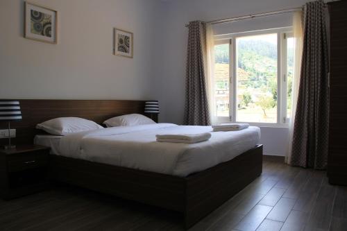 um quarto com uma cama grande e uma janela grande em Two Seas Residence em Ooty