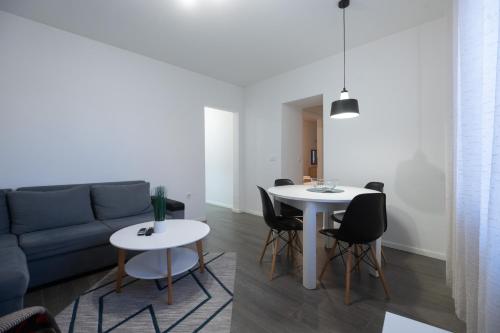 uma sala de estar com um sofá, uma mesa e cadeiras em Pyrotima Apartments em Zadar