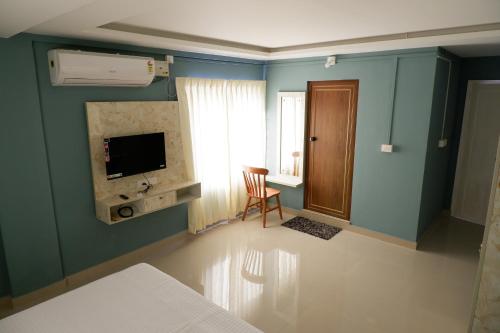 um quarto com uma cama, uma televisão e uma cadeira em Haya Residency em Alappuzha