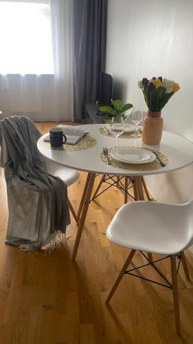 ein weißer Tisch mit zwei Stühlen und ein Tisch mit Blumen darauf in der Unterkunft Victoria Apartment in Narva