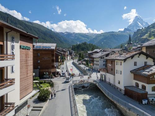 a view of a town with a river and mountains at Hotel Parnass in Zermatt