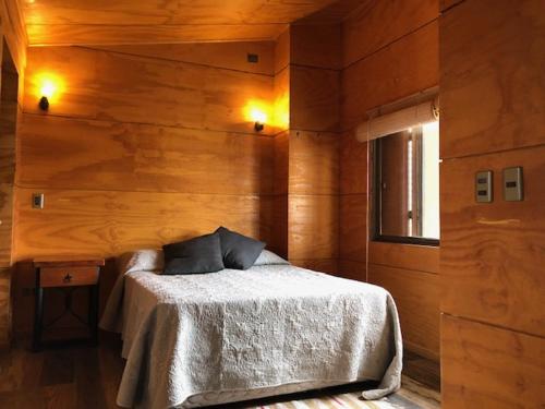 - une chambre avec un lit et un mur en bois dans l'établissement Tongoy Beach Tinyhouse, à Tongoy