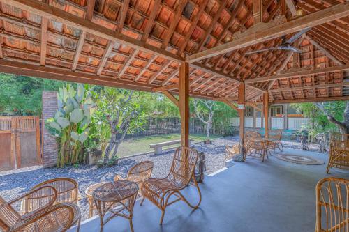 een patio met stoelen en tafels onder een houten pergola bij Yukke Tembi Homestay in Yogyakarta