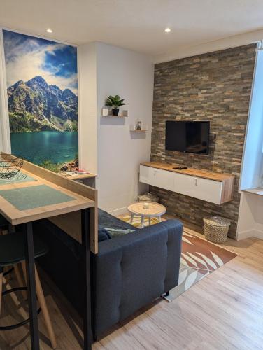 sala de estar con sofá azul y TV de pantalla plana en Appartement au cœur des alpes, en Albertville