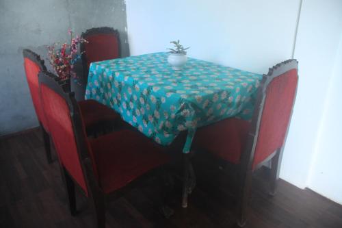 une table avec un chiffon bleu et des chaises rouges dans l'établissement Mukhia's HomeStay Amayras, à Darjeeling