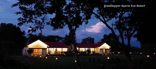 uma casa iluminada à noite com luzes em Grasshopper Acacia Eco Resort em Mādāri Hāt