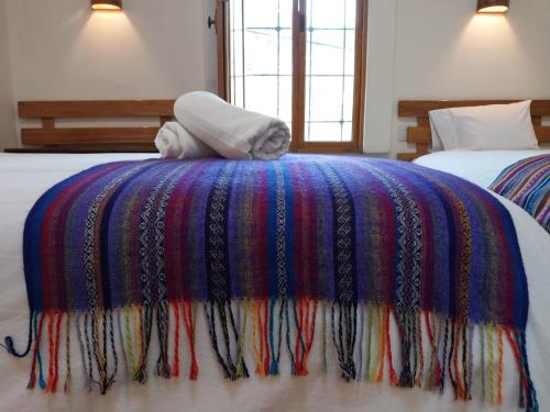 Una cama con una manta de colores encima. en Maison Fortaleza, en Cusco