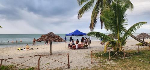 um grupo de pessoas em uma praia com guarda-sóis e o oceano em MAHAMBO BEACH hôtel em Mahambo