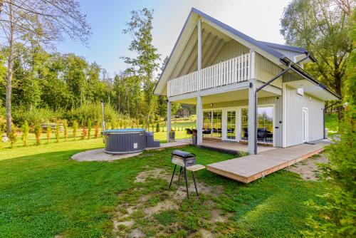 a house with a deck and a grill in the yard at Namelis ant ežero kranto "Giliaus Elingas" in Tytuvėnai