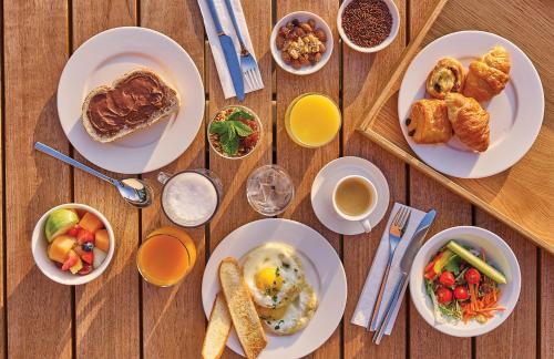 un tavolo in legno con piatti per la colazione e bevande di Hyatt Place Amsterdam Airport a Hoofddorp