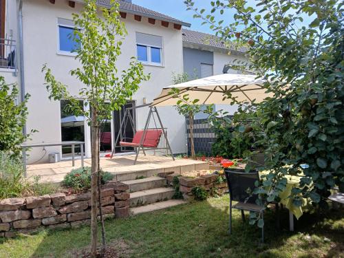 einen Garten mit einem Stuhl und einem Sonnenschirm in der Unterkunft Ferienwohnung Gartenblick Altlußheim - Netflix - parken - Küche - Klimaanlage - Shuttle zum Hockenheimring in Altlußheim