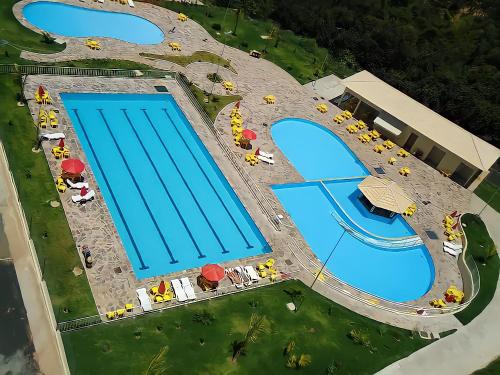 an overhead view of two large swimming pools at ÁGUAS TERMAIS NATURAIS nas PISCINAS com ÁGUAS QUENTES 24 HORAS acesso GRÁTIS aos PARQUES AQUÁTICOS dos RESORTS GOLDEN DOLPHIN GRAND HOTEL do SUPREME e do EXPRESS os melhores HOTÉIS RESORTS com PARQUE AQUÁTICO em CALDAS NOVAS Garanta JÁ PROMOÇÃO QUALIDADE in Caldas Novas