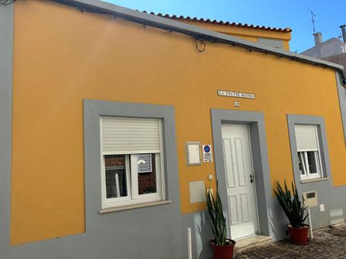 um edifício amarelo com duas janelas e uma porta em La petite maison em Portimão