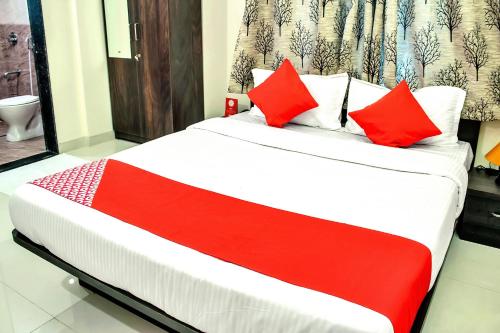 una cama con almohadas rojas en una habitación en Hotel O Homes Vardhan House 2, en Dāpuri