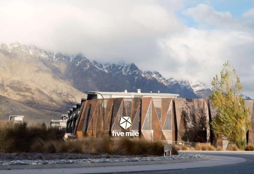 a building with a sign on it in front of a mountain at Sudima Queenstown Five Mile in Queenstown